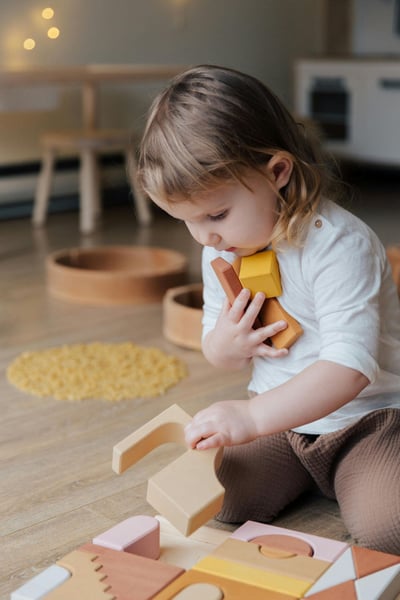 A young child sitting on the floor playing with wooden blocks.