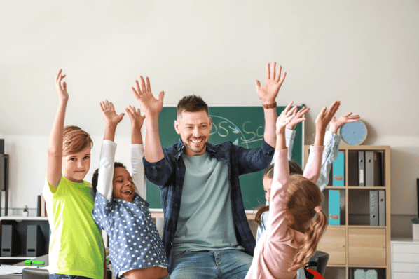 Group of happy children with teacher in classroom.