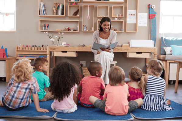Preschool teacher skills in action in the classroom reading to a group of children